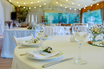 Table set with blank guest card, plate with white napkin and cutlery on table, copy space. Place setting at wedding reception. Table served for wedding banquet in restaurant