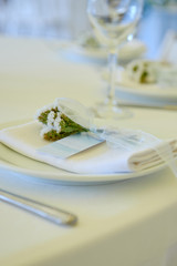 Table set with blank guest card, plate with white napkin and cutlery on table, copy space. Place setting at wedding reception. Table served for wedding banquet in restaurant