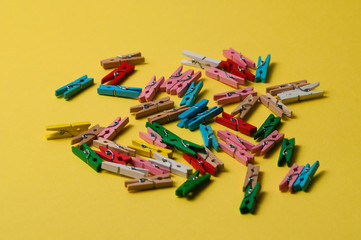 Multicolored decorative wooden clothespins on yellow background