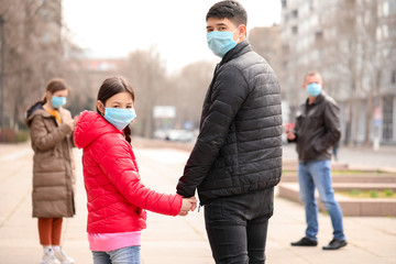 Obraz premium Asian family wearing protective masks on city street. Concept of epidemic