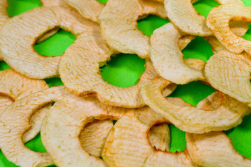 Chips from dried apples, sliced in thin circles. Photographed on a green background. Background for healthy eating and vegetarianism.