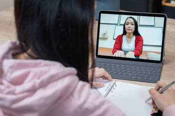An asian women talking while video chatting with colleague.