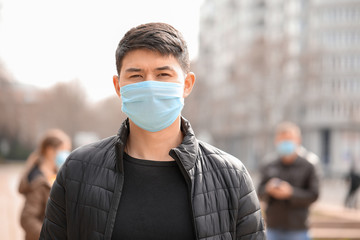 Asian man wearing protective mask on city street. Concept of epidemic