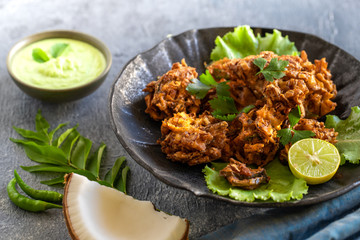 Indian cuisine Indian food. pakora traditional Indian deep-fried snack. pakoras on black plate with coconut chutney sauce curry leaves. national appetiser authentic vegetarian Asian food. travel food.