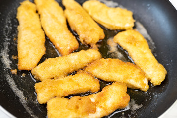 Frying chicken meat with breadcrumbs in the frying pan