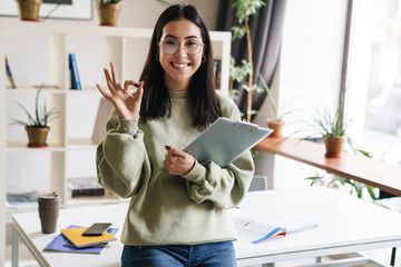 Cheery young girl student indoors holding clipboard.