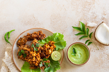 Indian cuisine Indian food. pakora traditional Indian deep-fried snack. pakoras on black plate with coconut chutney sauce curry leaves. national authentic vegetarian Asian food. travel food. top view.
