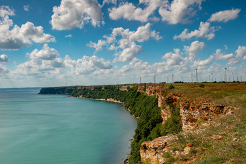 a bay with huge rocks and in the distance there are windmills