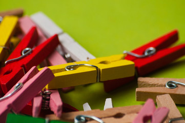 Multicolored decorative wooden clothespins on a green background, macro closeup, copy space