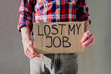 Man worker in plaid shirt with cardboard sign LOST JOB. Jobless, unemployment concept. Asking for...