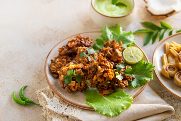 Indian cuisine Indian food. pakora traditional Indian deep-fried snack. pakoras on black plate with coconut chutney sauce curry leaves. national appetiser authentic vegetarian Asian food. travel food