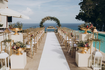 Wedding decorations. The ceremony area in the villa by the pool overlooking the sea is decorated with flower arrangements, golden vases and candles