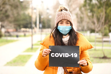 Young Asian woman wearing protective mask on city street. Concept of Coronavirus epidemic