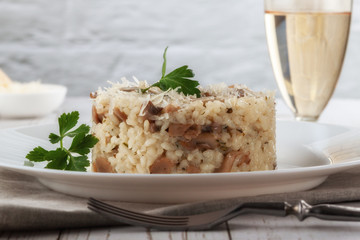 Wild mushroom risotto with parsley and parmesan on a white wooden background
