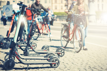 Fototapeta premium Background of sharing electric scooter parked on sidewalk summer sunlight using phone mobile app for rent. use in smart urban city in europe help transportation, traffic, safe environment pollution