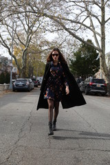 A female model in a dress walks down a street in Brooklyn