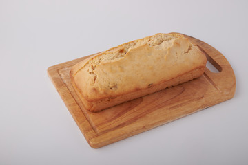Checkered napkin, pieces of muffin with raisin on plastic cutting board on wooden table