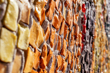 A fragment of a wall with a multicolored mosaic that goes into perspective.Abstract texture,creative background.Selective focus,blurred background.Copy space for text