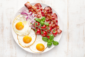 Fried eggs with bacon on white background