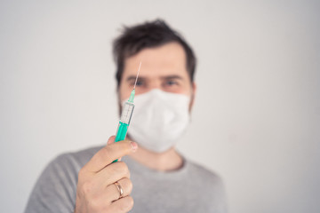 man in a medical mask with a syringe in his hands on a light background