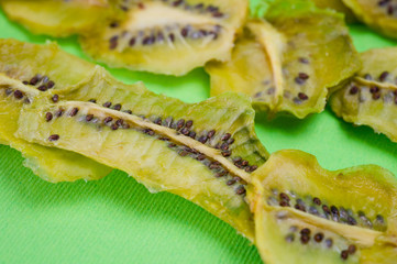 Dried kiwi chips, sliced in thin circles. Shot on a green background. Background for vegetarianism and healthy eating.
