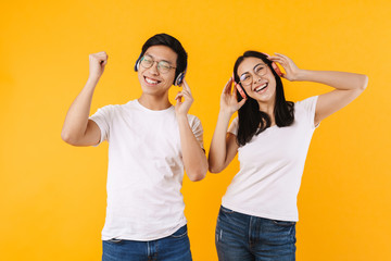 Image of multinational couple in headphones listening music and dancing