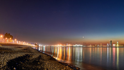 Fototapeta premium Beautiful night view from Sea Beach to Illuminated cityscape. Reflections of lights in Black Sea in Batumi, Adjara, Georgia.
