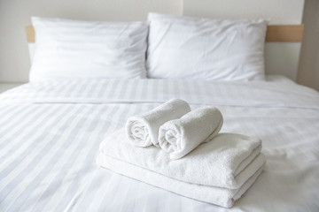 Fototapeta na wymiar Freshly laundered fluffy towels on bed in hotel