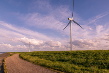 Road on coast near sea and wind electric mill.