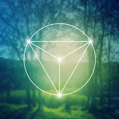 Merkaba sacred geometry spiritual new age futuristic illustration with interlocking circles, triangles and glowing particles in front of blurry natural photographic background