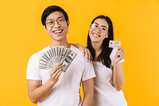 Image of smiling multinational couple showing dollars and credit card