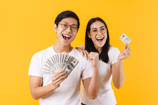 Image of excited multinational couple showing dollars and credit card