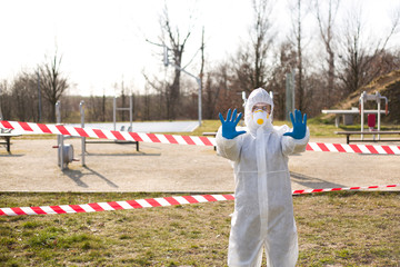 Obraz premium Osoba w kombinezonie ochronnym i rękawiczkach zakazuje wejścia na obiekt sportowy w czasie pandemii