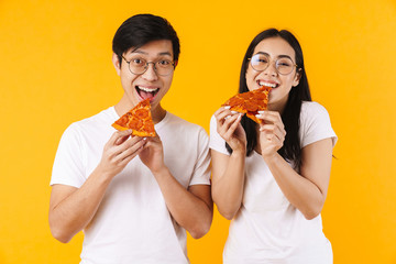 Image of cheerful multinational couple smiling and eating pizza