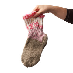 female hand holds a pair of knitted woolen socks, warm clothes