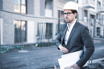 Mann im Anzug mit Helm und Weste auf einer Baustelle