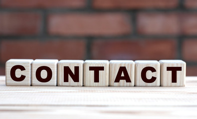 Obraz premium concept word CONTACT on cubes against the background of a brick wall