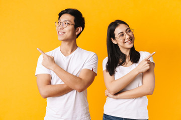 Image of smiling multinational man and woman pointing finger aside
