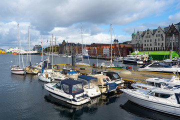 Fototapeta na wymiar UNESCO WHS Bryggen in the background of Bergen's port and a lot of boats are parked over there. August 2019