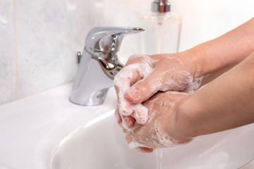Woman using soap and hot water to wash her hands. Coronavirus pandemic prevention.