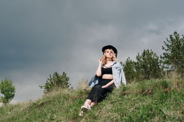 beautiful young woman in black against a landscape of sky and field