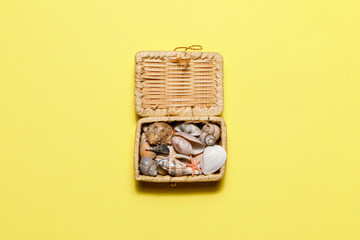 Summer time concept with seashells starfish and chest on yellow background with copyspace. Rest on the beach