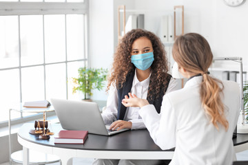 Female lawyer in protective mask working with client in office