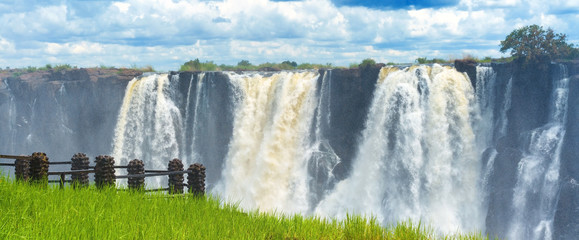 Panorama view with dramatic clouds and waterfall at Victoria Falls on the Zambezi River, Zimbabwe,...