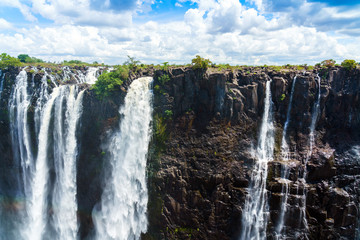 Panorama view with dramatic clouds and waterfall at Victoria Falls on the Zambezi River, Zimbabwe,...