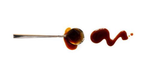 Spoon with teriyaki and soy sauce splash isolated on white background, top view. Close-up seasoning...