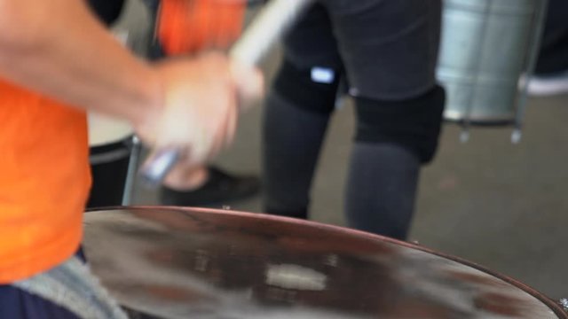 Superb close up shot of a drummer in a fast rhythmic beat on a single drum during a performance in a troupe of drummers.