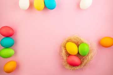 Beautiful easter eggs painted in yellow, red and green pastel colors on a pink background.