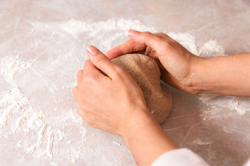 process of baking health bread at home. closeup woman hands kneading dough from rye flour on marble countertop in bright kitchen