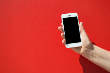 Close up on holding mobile smart phone over red background. Working remotely with information, modern communication lifestyle mock up display.